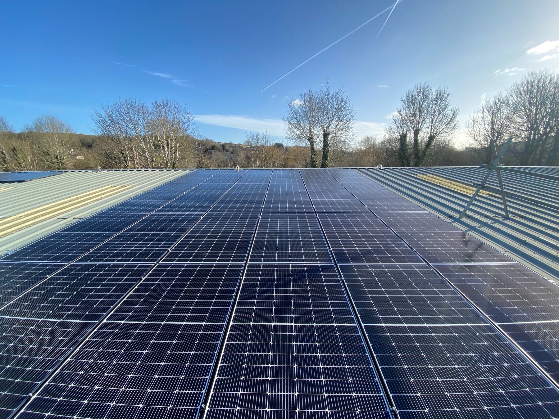 Large black solar panel array installed on a roof against a bright sky in England