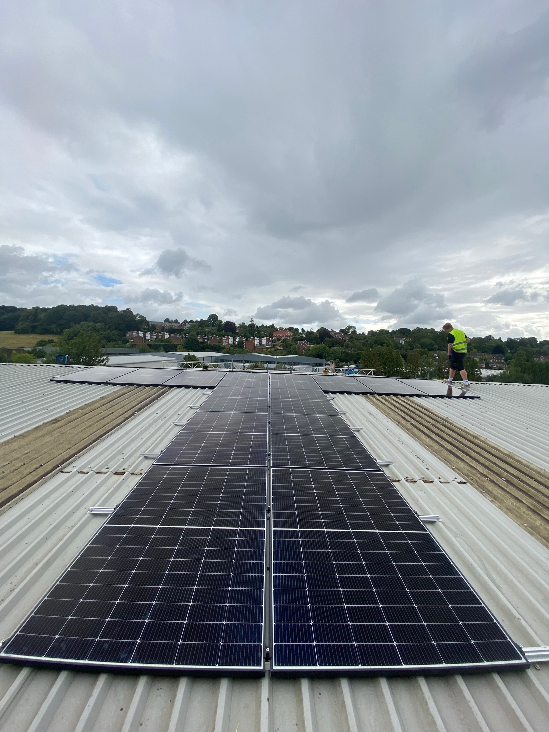 Installer fitting solar panels on a large commercial metal roof